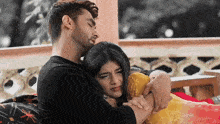 a man and a woman are hugging each other on a couch .