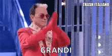 a man in a red suit and sunglasses is making a funny face while standing on a stage .