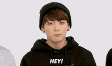 a young man wearing a black beanie and a black hoodie with the words hey on it .