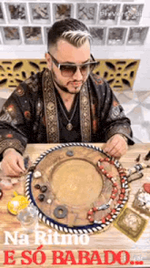 a man wearing sunglasses is sitting at a table with a circle of beads .