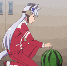 a girl in a red and white outfit is kneeling down next to a large watermelon