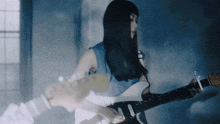 a woman is playing a guitar in a dark room with a window in the background