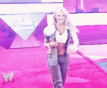 a woman walking on a pink carpet with a w logo in the background