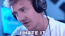 a man wearing headphones is saying `` i hate it '' while sitting in front of a microphone .