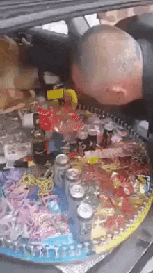 a man is laying in the back of a car surrounded by bottles and cans