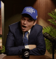 a man in a suit and tie is wearing a blue hat that says america first