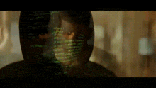 a man 's face is projected on a screen with a lot of green letters