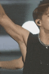 a close up of a man 's armpit while wearing a black tank top and a necklace .