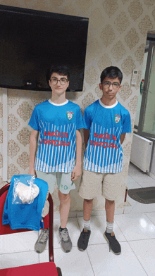 two boys wearing blue and white striped shirts with the word istanbul on the front stand next to each other