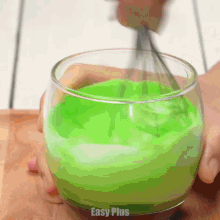 a person is whisking green liquid in a glass with easy plus written on the bottom of the glass