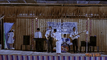 a man playing a guitar in front of a sign that says temasha on it