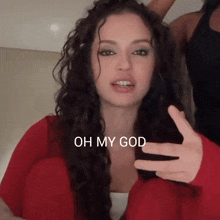 a woman with long curly hair says oh my god with her hand