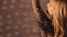 a woman in a sequined dress is dancing with her arms outstretched .