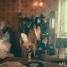 a woman in a dress stands in front of a mirror with the letters ms on the bottom right