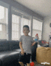 a young boy is standing in a living room holding a bottle .
