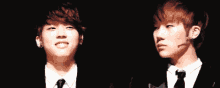 two young men in suits and ties are standing next to each other and smiling .
