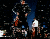a man in a leather jacket stands in front of a group of people dancing