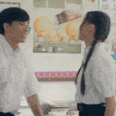 a boy and a girl are looking at each other in front of a bulletin board