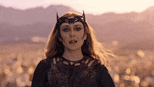 a woman in a costume with a crown on her head stands in a field .