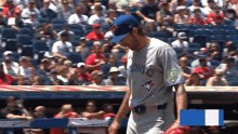 a toronto blue jays baseball player stands on the dugout
