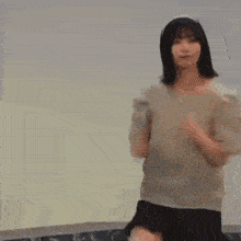 a woman in a white shirt and black skirt is dancing in a room .