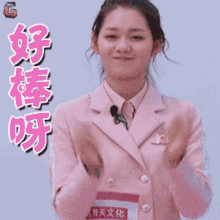 a woman in a pink suit is clapping her hands in front of a sign that says g