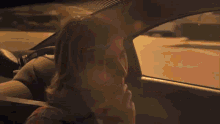 a woman is sitting in a car looking out of the window
