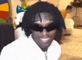 a man with dreadlocks is wearing sunglasses and a white shirt .