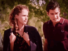 a man and a woman are standing next to each other and the man is wearing a red fred perry shirt