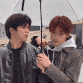 a man with red hair is holding an umbrella next to another man