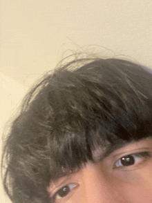 a close up of a person 's eyes with a white wall in the background