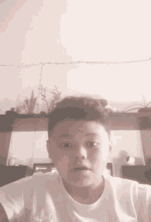 a young boy in a white shirt is making a funny face while looking at the camera