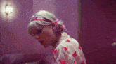a woman wearing a headband and a pink shirt is standing in a room .