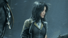 a woman with long black hair is wearing a black jacket with gold trim