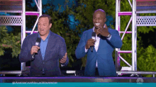 two men standing next to each other with microphones in front of a screen that says americanninjawarrior