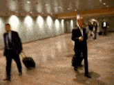a man in a suit is pulling a suitcase
