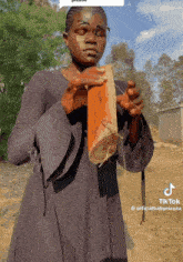 a woman wearing glasses holds a piece of wood in her hands