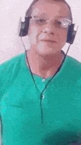 a man wearing headphones and a green shirt is looking at the camera .