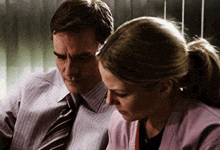 a man in a striped shirt and tie sits next to a woman in a pink shirt
