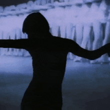 a silhouette of a woman is dancing in front of a projection of a crowd of people .