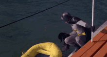 a man in a batman costume is standing on a dock next to a yellow raft .