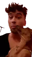 a man is holding a small brown dog and the dog is licking his face