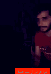 a blurry picture of a man in a red shirt with arabic writing