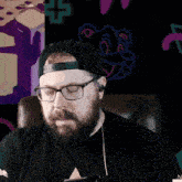 a man with a beard wearing glasses and a hat with the letter a on it