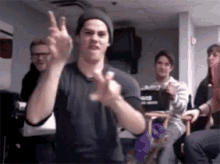 a man in a black shirt is making a peace sign with his hands