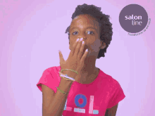 a girl wearing a pink lol shirt covers her mouth with her hand