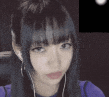 a close up of a woman wearing headphones and a purple top