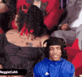 a man wearing headphones sits in a crowd with the name reggiecuhh in the corner