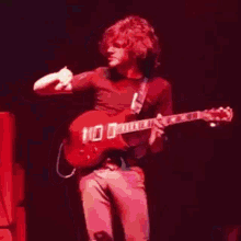 a man is playing a guitar with the number 100 on the neck