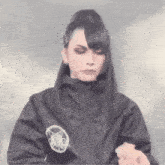 a woman wearing a black jacket and a ponytail is holding a piece of food in her hand .